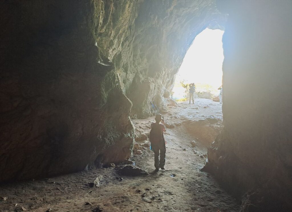 Inside Nestor’s Cave near Voidokilia Beach, with hikers silhouetted against the bright cave entrance in the Peloponnese.