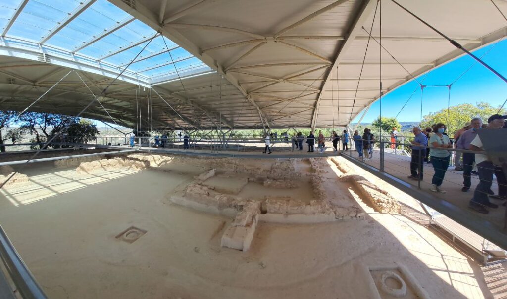 Visitors walking on elevated paths above the ruins of Nestor’s Palace in Pylos, Greece, under a protective roof at the archaeological site.