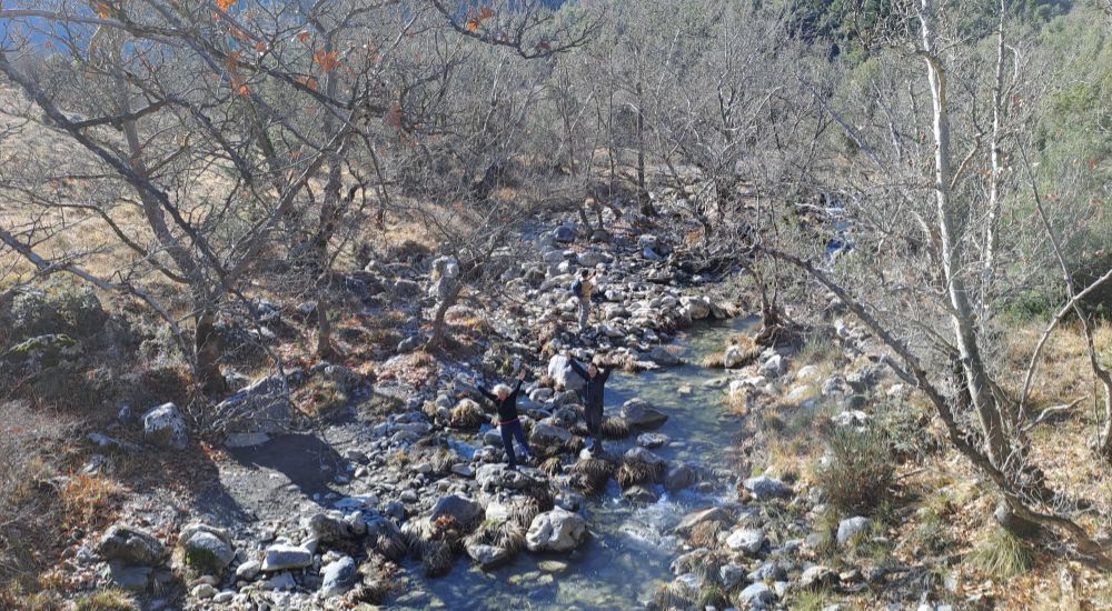 Tzavarenas Stone Bridge and hikers by the Mylaontas river