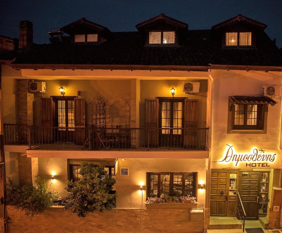 Dimosthenis Hotel exterior lit with a sign in Greek in Paiko Mountain Greece. 