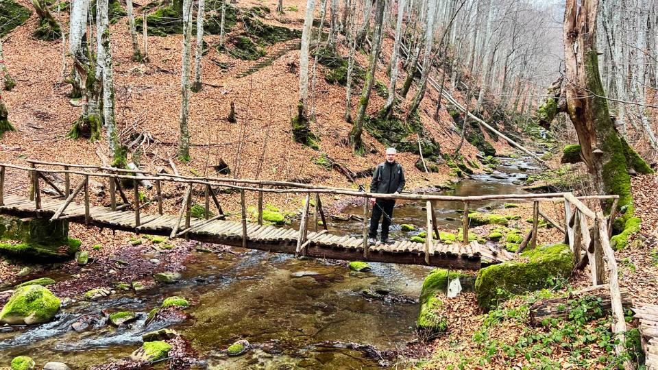 Joseph of Planet Greece stands on a river wooden bridge in Paiko mountain northern Greece.