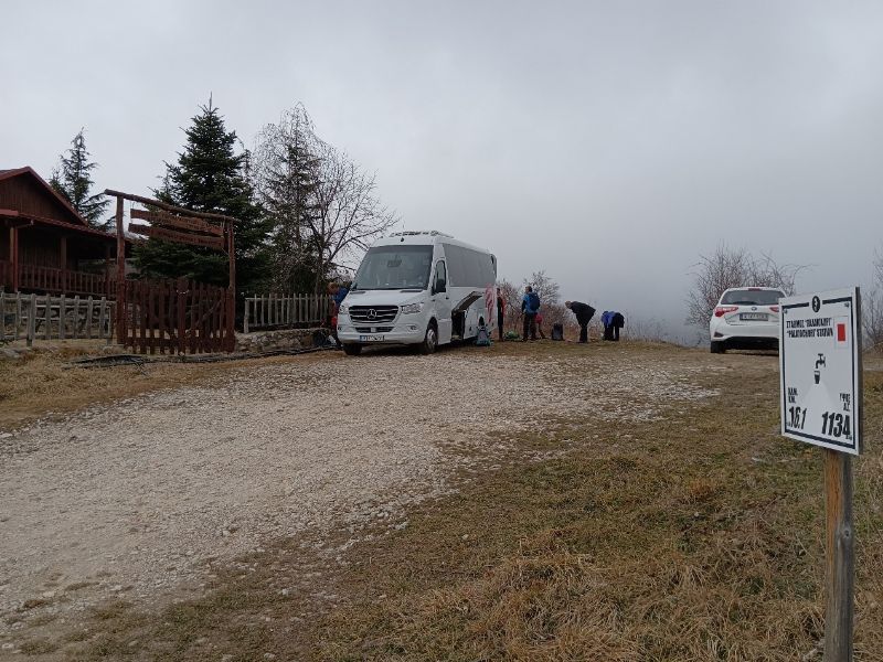 Hikers changing shoes in front of a coach vehicle in Paiko mountain Greece. 