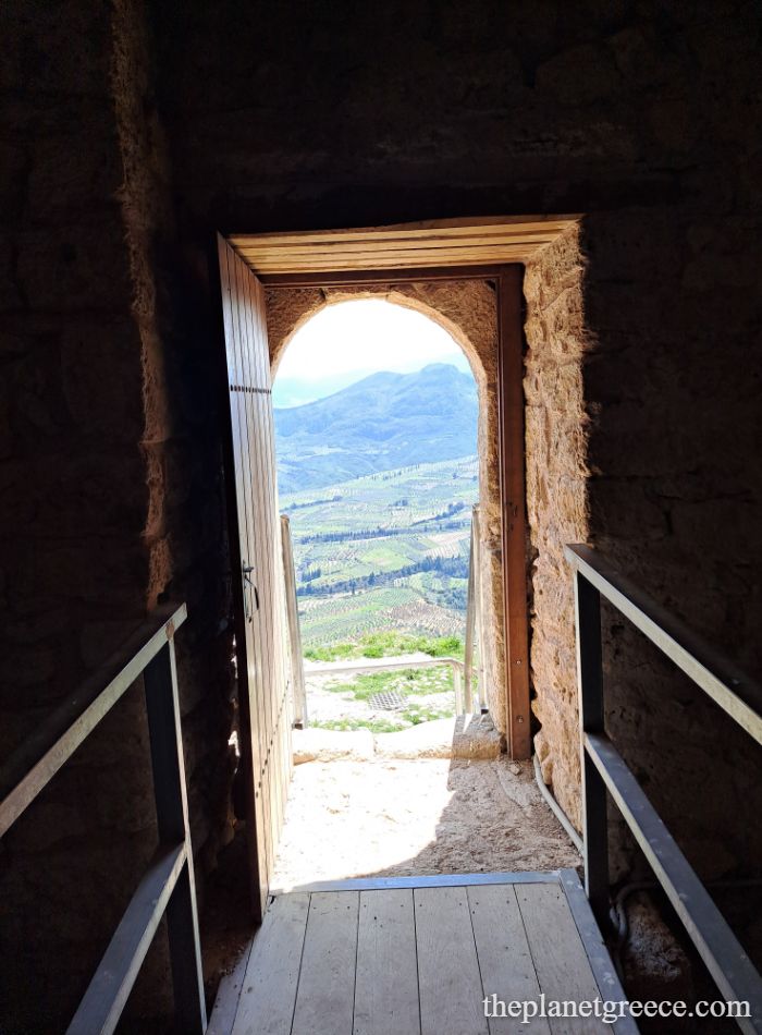 Looking out from a castle doorway at Acrocorinth, with scenic views of green hills and valleys below.