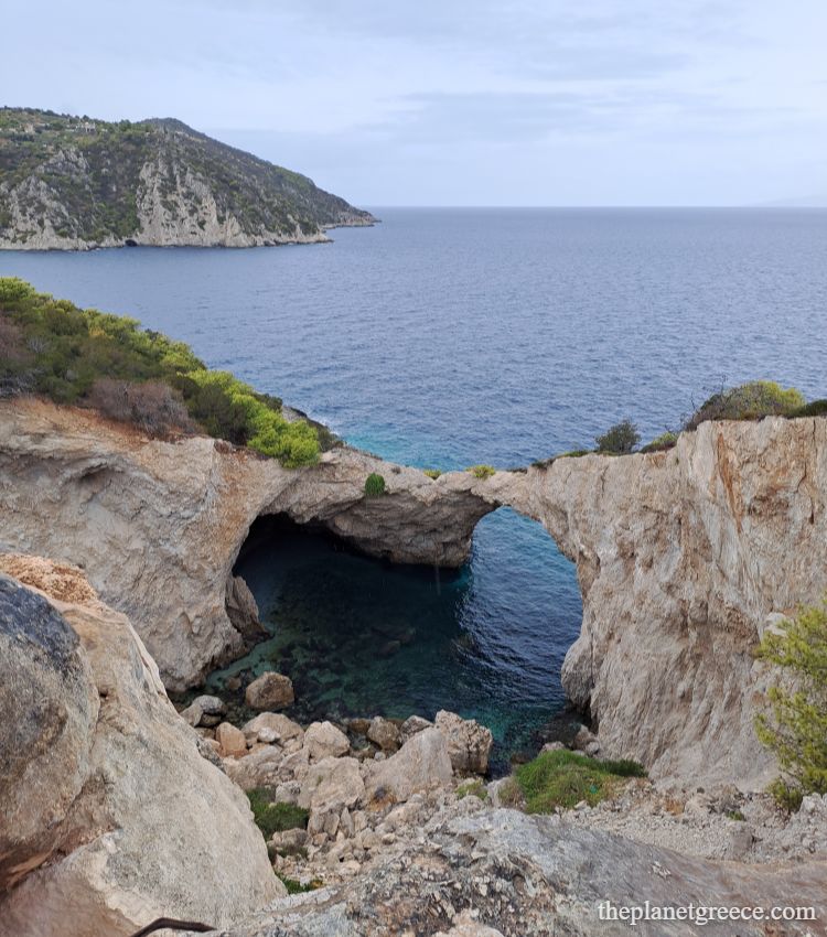 Turquoise sea and layered rock formations along the Sterna to Melagkavi Lighthouse coastal hike in Loutraki Greece.