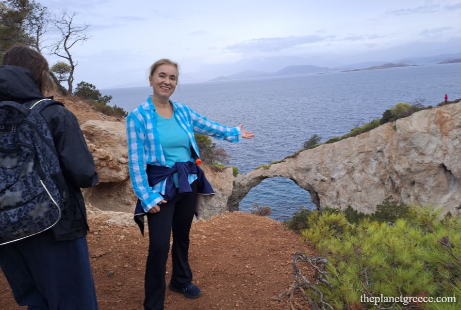 Evgenia pointing to the natural rock arch on the hike to Melagkavi Lighthouse in Loutraki Greece.