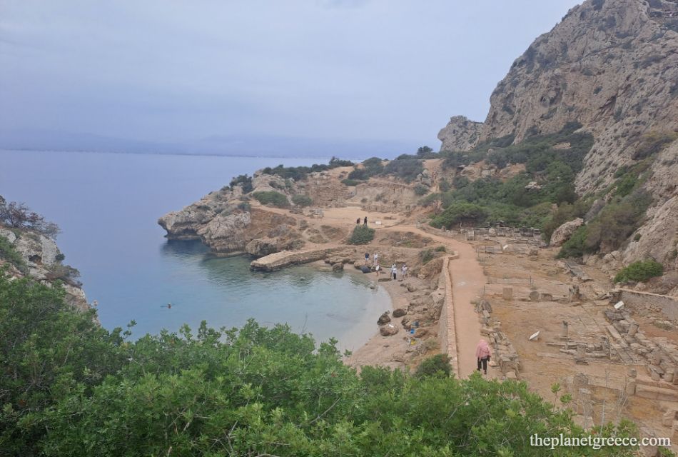 Ancient Heraion ruins by the sea in Loutraki, Greece, with a small beach and calm turquoise water.