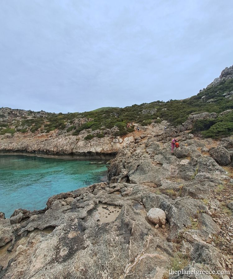 Turquoise cove and rocky cliffs along the hike to Melagkavi Lighthouse in Loutraki Greece.